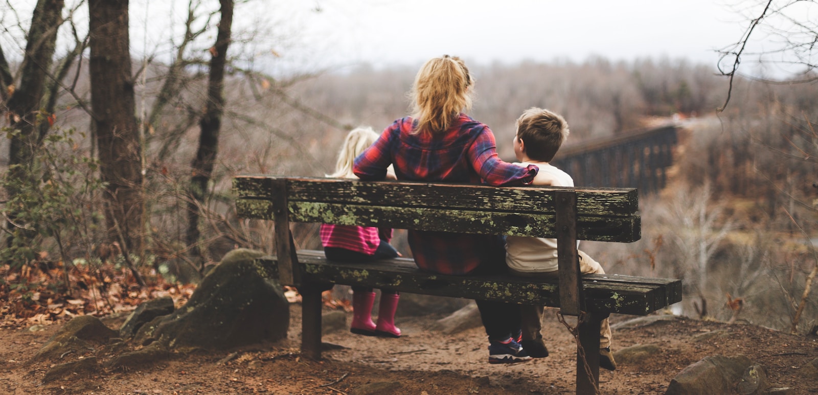 Photo by Benjamin Manley woman between two childrens sitting on brown wooden bench during daytime