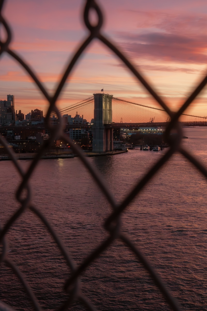 Brooklyn bridge at sunset, seen through chain link.